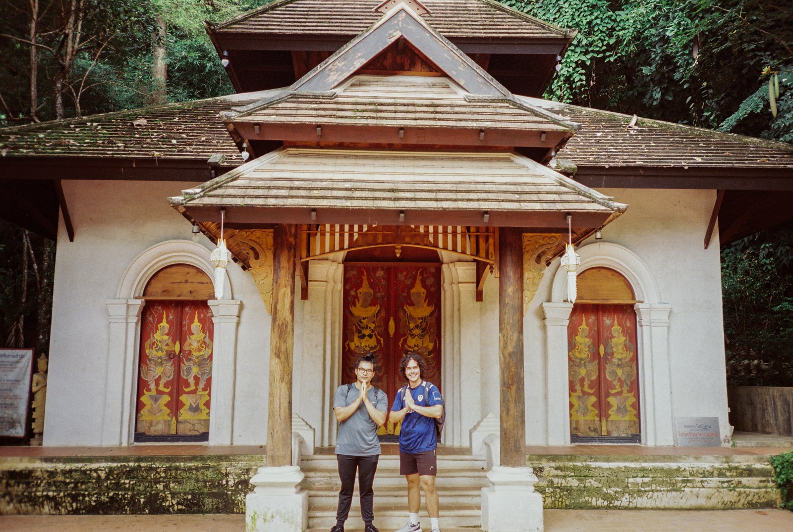 Two people in front of a small white temple