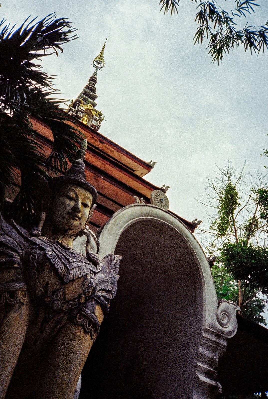 A guardian statue below a temple roof