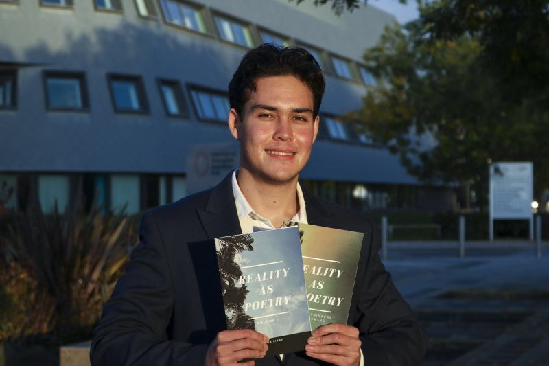 James in a suit, holding his two books